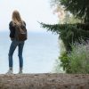 湖のほとりに立つバックパックの旅行者
