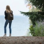 湖のほとりに立つバックパックの旅行者